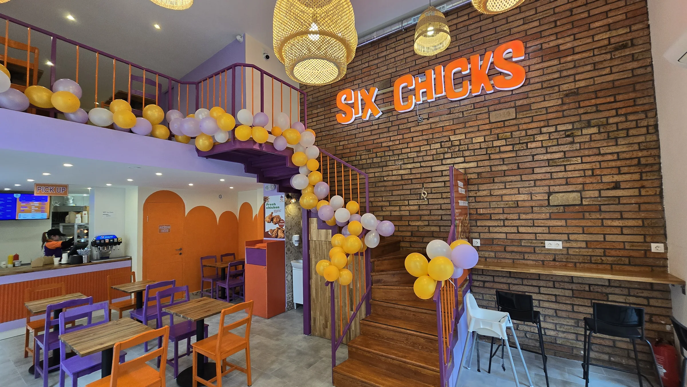 Inside Six Chicks: purple and orange chairs, a brick wall and the Six Chicks sign